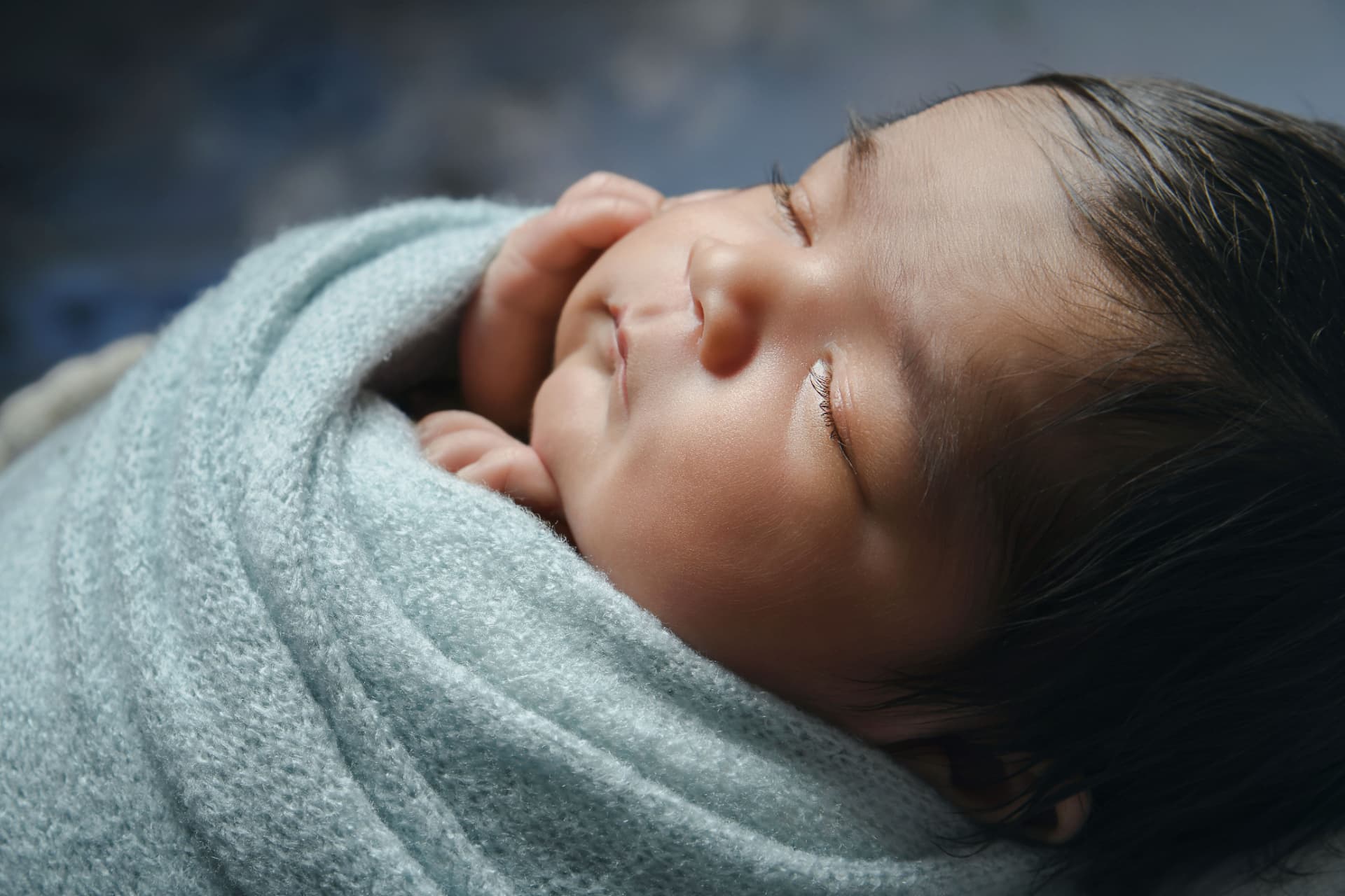 Sleeping newborn wrapped in a soft blue blanket